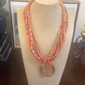 Orange/coral beaded necklace with shell-like pendant.